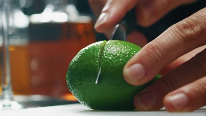 专业调酒师的特写镜头正在切石灰，以便在酒吧或迪斯科俱乐部为顾客准备含冰块的酒精鸡尾酒。