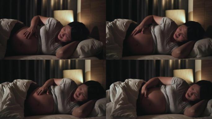孕妇晚上睡觉前在卧室休息，对肚子里的宝宝有一种感情和快乐