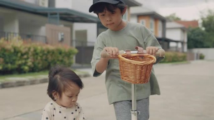 小男孩和他的妹妹骑着一辆踏板车。