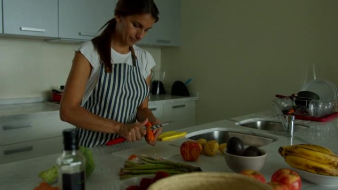 拉丁美洲年轻的素食主义者在家准备午餐剥胡萝卜