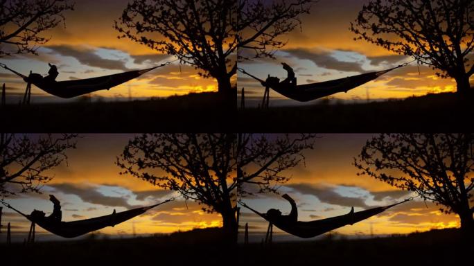 日落时在吊床上看书的女人的SLO MO剪影