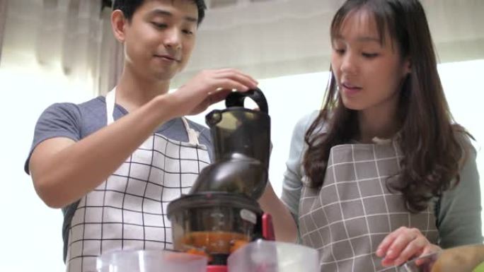 亚洲夫妇准备蔬菜和水果，并使用榨汁机进行冷榨果汁