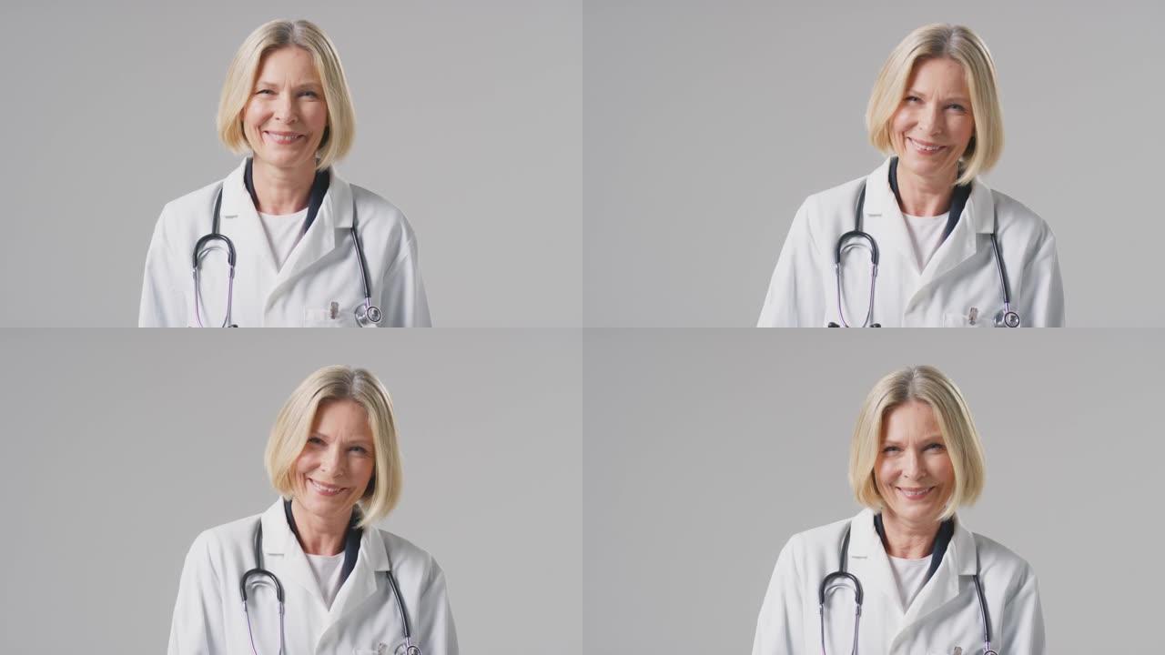 工作室肖像成熟的女医生与听诊器穿着白色外套在素色背景下