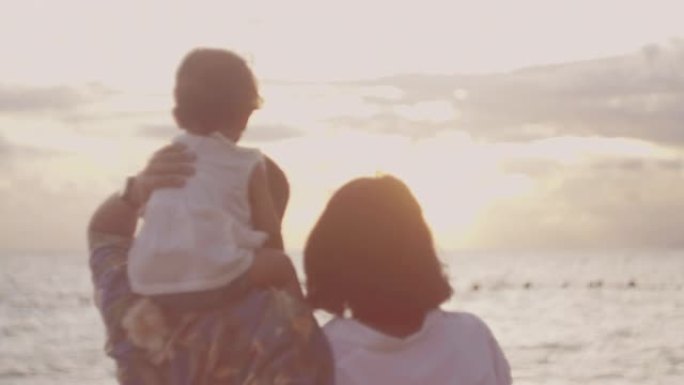 白种人家庭牵着手在日落时沿着海滩散步