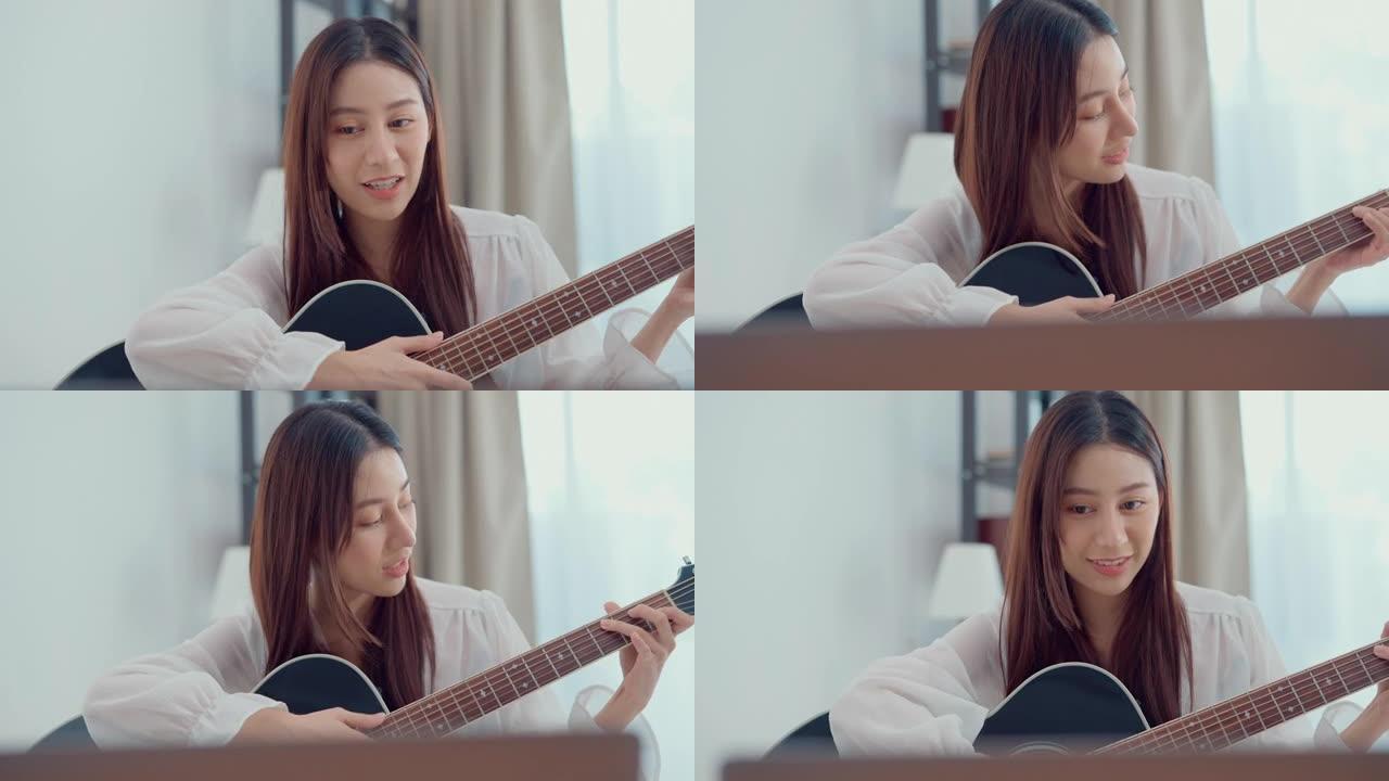 快乐的年轻女子专注于学习用笔记本电脑弹吉他坐在家里的客厅