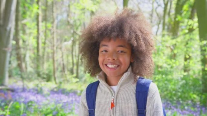 微笑男孩的肖像带着风铃草穿过春天的林地-慢动作拍摄