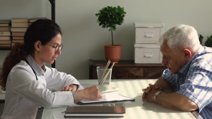 年轻女治疗师向老年患者解释医疗保险福利。