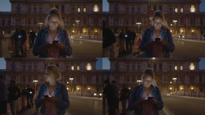 SLO MO女人晚上在罗马的一座桥上行走时使用智能手机