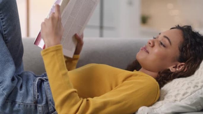 4k视频片段，一名年轻女子在沙发上放松并在家看书