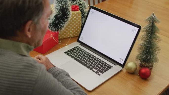 白人高级男子坐在桌子旁，在笔记本电脑上在家进行视频通话，屏幕上有复制空间