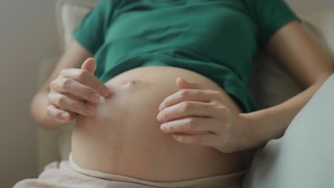孕妇的特写镜头期待母亲抚摸怀孕的肚子。