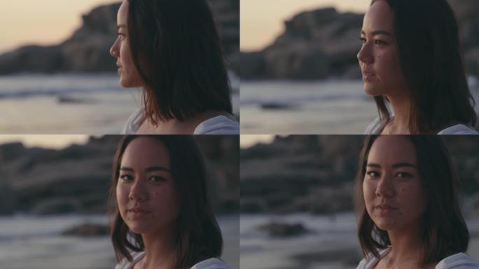 4k视频片段，一个迷人的年轻女子独自站在海滩上，在日落时沉思