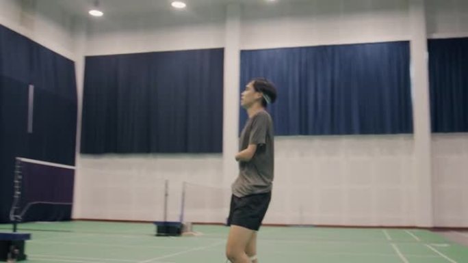 亚洲残疾人男子羽毛球运动员在羽毛球场跳跃射击。