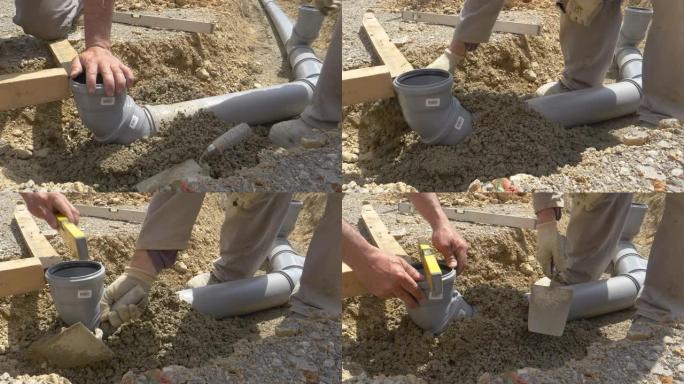特写: 水管工使用水平和新鲜的混凝土来掩埋宽阔的污水管。