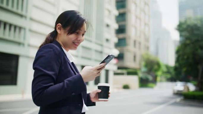 女商人在城市使用智能手机并拿着咖啡杯