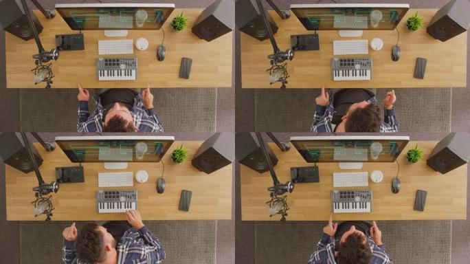 工作站上的男音乐家的俯视图，在录音室中使用键盘和麦克风跳舞和唱歌以及慢动作的曲目拍摄