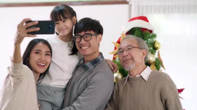 4K UHD手持多代亚洲快乐家庭在装饰完装饰品后与圣诞树一起自拍。