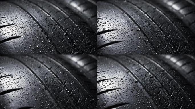 黑色背景下的新车夏季轮胎胎面花纹上的水滴