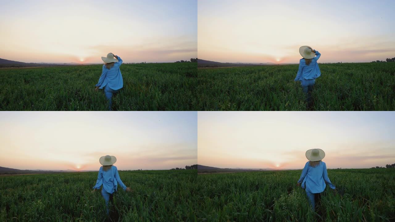 慢动作特写后视图一名戴着草帽的美丽年轻女子在日落时在麦田里奔跑和跳跃