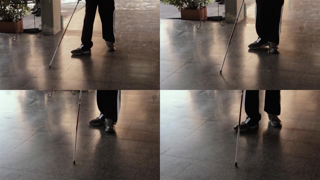 一名年轻男子，手杖白走在学校的走廊上。低角度视图。