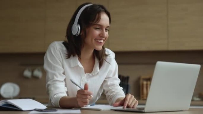 戴着耳机的年轻迷人女人在家与家教进行电子学习