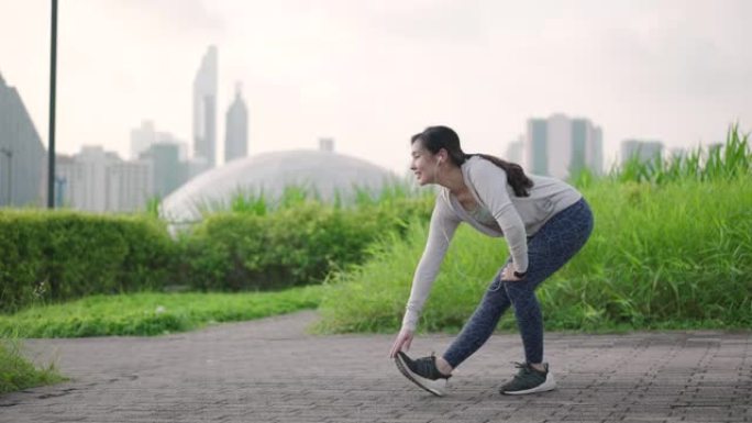 年轻的亚洲妇女在城市户外跑步前进行热身运动