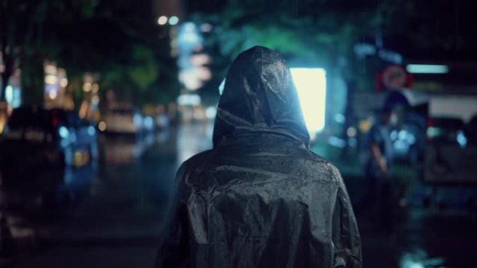 年轻人在下雨的时候穿上雨衣，在潮湿的天气里走回家