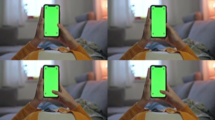 女士无法辨认的女人在家里的沙发上使用带有色度屏幕的智能手机