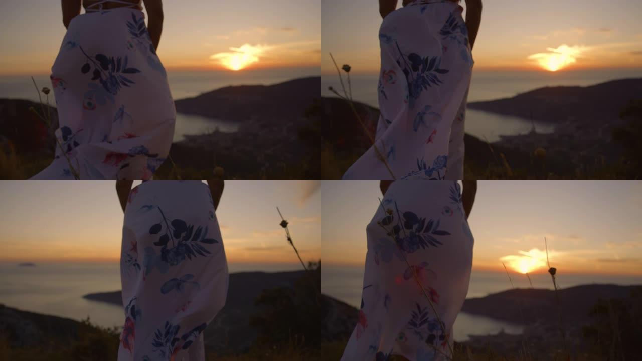 穿着白色连衣裙的SLO MO无法辨认的女人，享受着令人惊叹的海景和美丽的日落