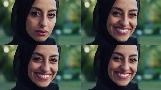 特写美丽的年轻阿拉伯女人看着相机，带着绿色背景微笑的肖像。戴着头巾的穆斯林女少年在公园里享受新鲜空气