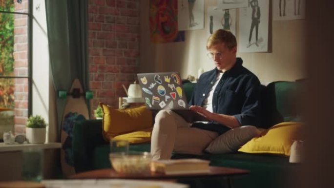 青少年男性电子商务企业家使用笔记本电脑，做远程工作。英俊的男人坐在沙发上，用研究来集思广益。阳光时尚