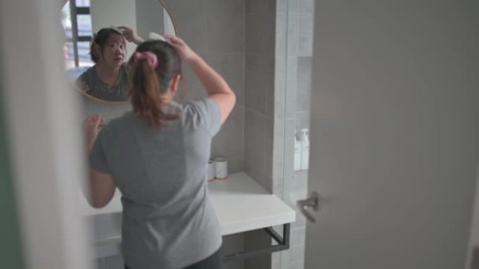 亚洲中国身体积极的女人扎着头发准备在家锻炼，享受周末在家对着镜子化妆