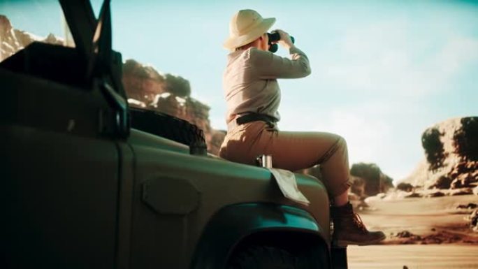 沙漠之旅: 美丽的女性旅行者坐在越野SUV的引擎盖上看着双筒望远镜，规划着充满惊奇和探索的路线。穿越