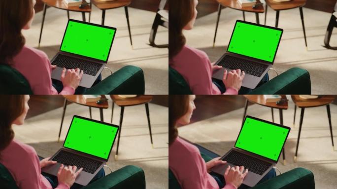 年轻的成年女性在带绿屏模拟显示的笔记本电脑上的家庭阁楼公寓工作。有创造力的女性浏览网络，在社交媒体上