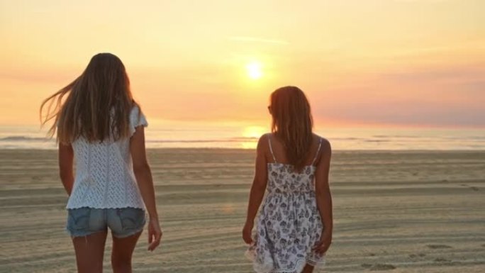 WS两名年轻妇女在日落时在海滩上散步