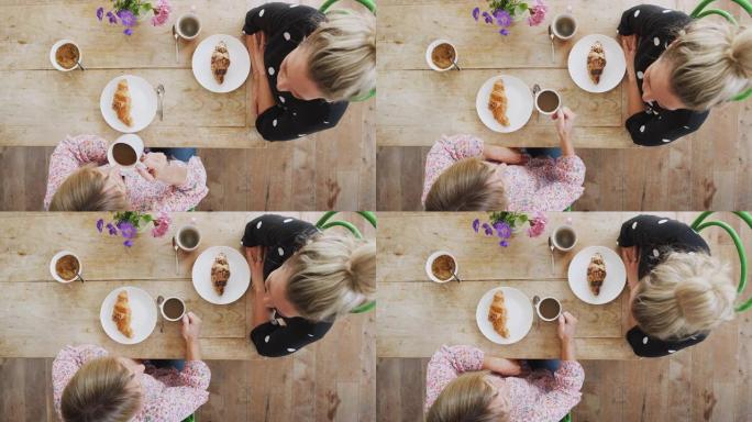咖啡店里两个女性朋友的俯视图以社交距离的方式见面