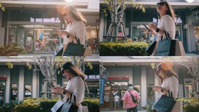 亚洲年轻女子带着购物袋走在城市街道上