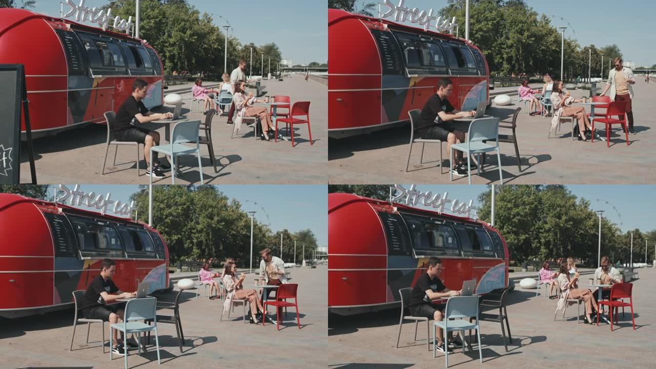 夏天坐在户外咖啡馆的人们坐在食品卡车上