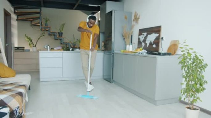 非洲裔美国男子在厨房洗地跳舞的慢动作用耳机听音乐