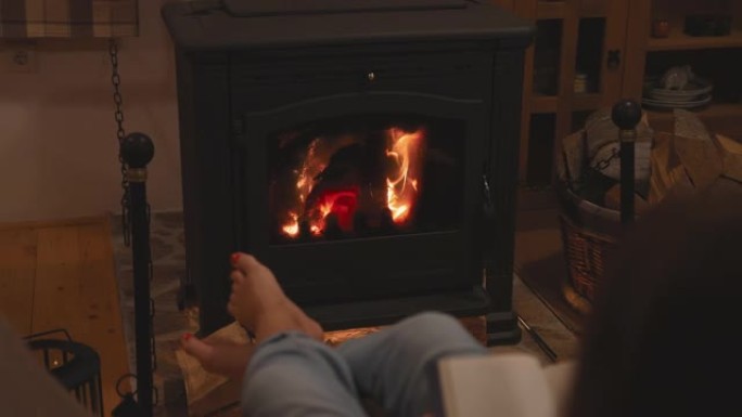 女人在家里壁炉旁的扶手椅上放松时看书