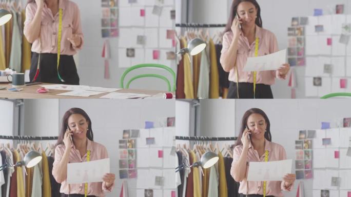 在手机通话中使用卷尺的女性时装设计师讨论在工作室工作的设计