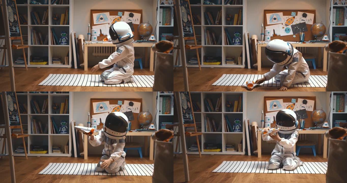 梦想太空旅行。穿着太空服的快乐小孩，头盔扮演火箭飞船飞行员，在他的房间里飞行玩具