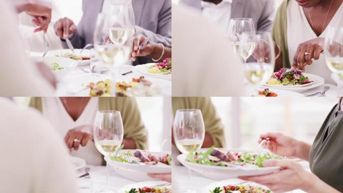 人们在餐桌上吃东西的特写镜头。餐馆里的男人和女人举行健康的晚宴。一群朋友在吃绿色沙拉配白葡萄酒。家人