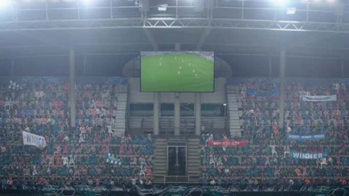 足球足球锦标赛体育场比赛，在记分牌屏幕上放大显示进球的重复。一群球迷欢呼，尖叫，玩得开心。体育频道电