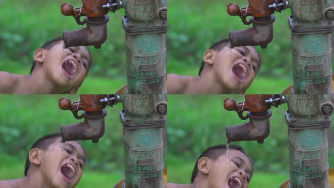 农村的一个孩子正慢慢地拿着一根饮用水管，带着幸福的微笑，这是一个在贫穷国家发现的古老人物。
