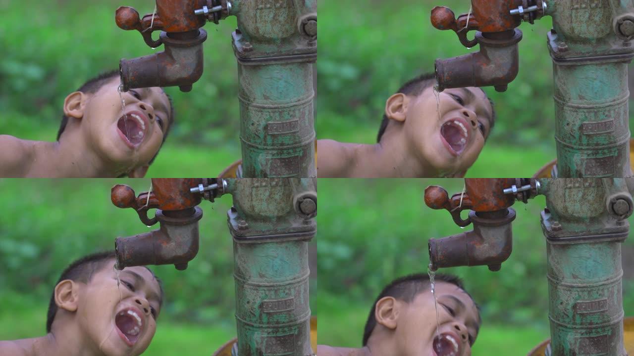 农村的一个孩子正慢慢地拿着一根饮用水管，带着幸福的微笑，这是一个在贫穷国家发现的古老人物。