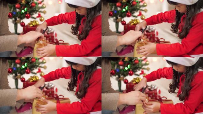 小女孩在母亲的帮助下为圣诞节打包礼物