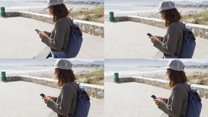 在海边阳光明媚的长廊上使用智能手机的混血妇女