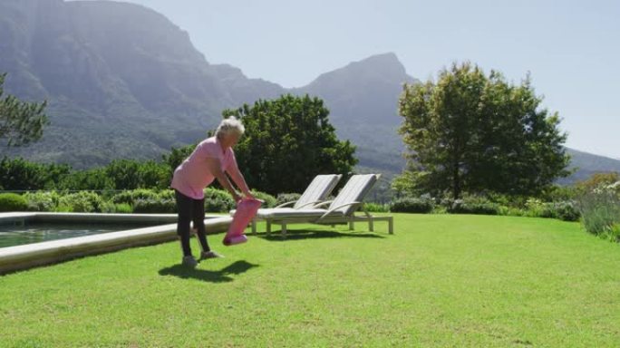 高加索老人在阳光下在花园里锻炼瑜伽垫
