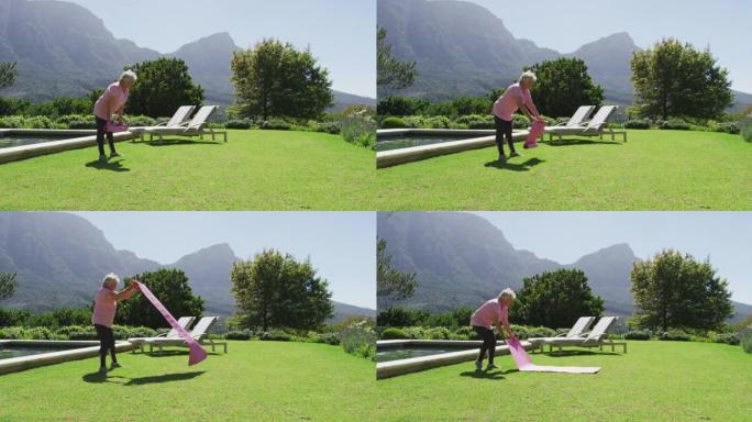 高加索老人在阳光下在花园里锻炼瑜伽垫